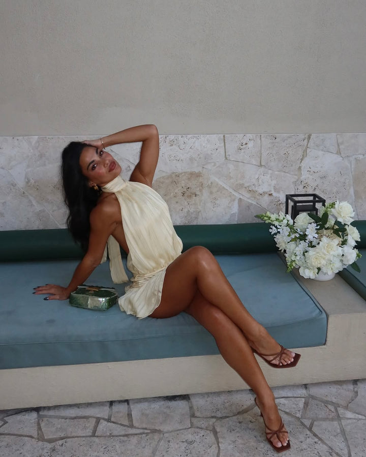 Fashionable cream halter mini dress, perfect as a versatile summer dress or elegant vacation wear.