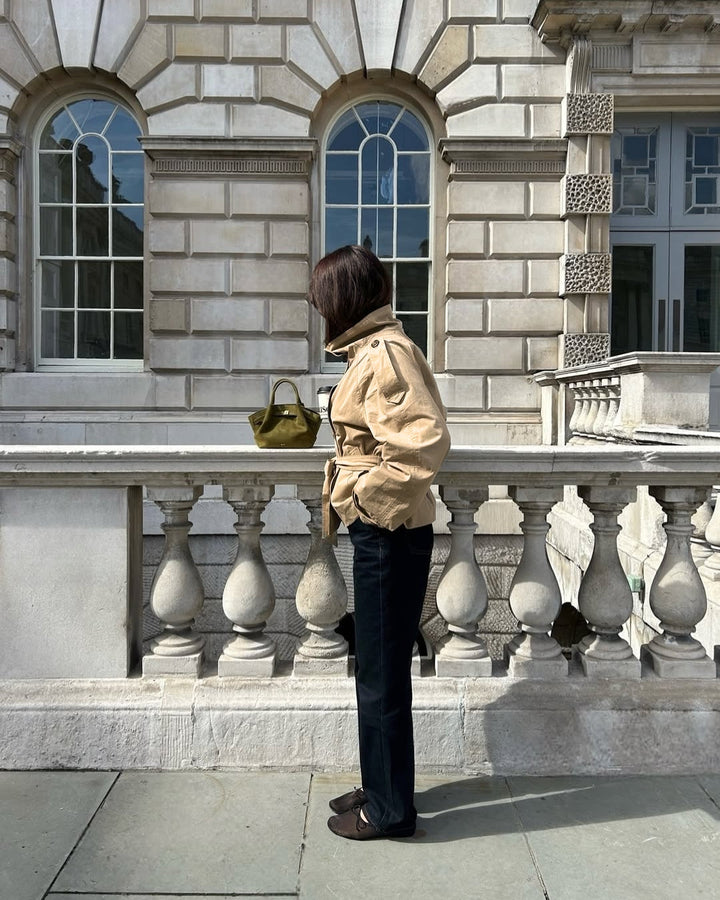 Fashionable women's cropped belted trench coat, double-breasted, offering a modern and elegant silhouette.