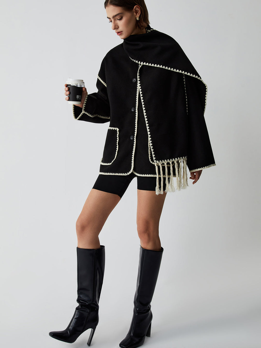 Precisely tailored women's black jacket paired with a fashionable fringe scarf, a key piece for elegant outerwear.
