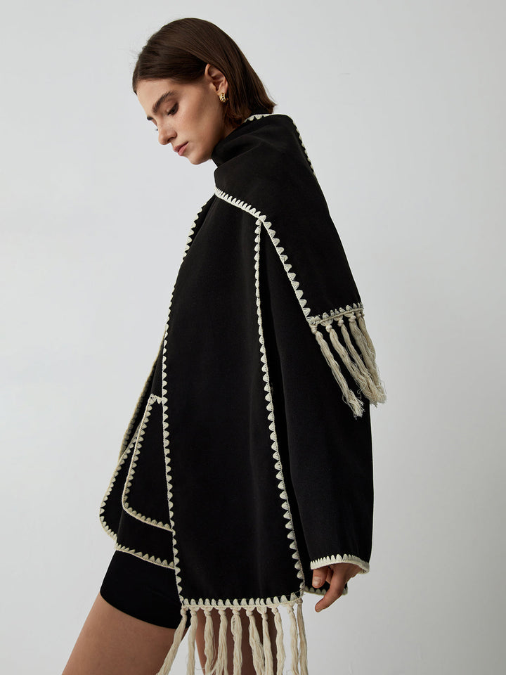 Women's tailored black jacket complemented by an integrated fringe scarf, offering elegant and unique outerwear style.