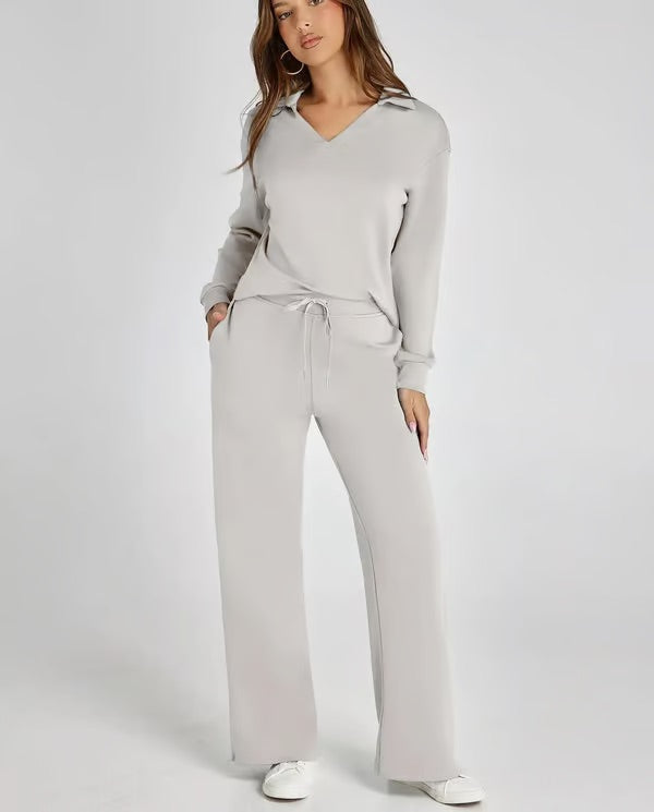 Woman relaxing at home in a comfortable two-piece lounge set with elegant collared top & drawstring pants.