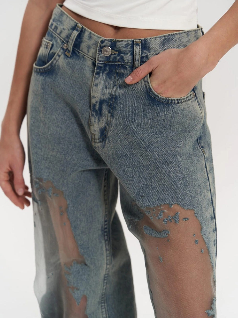 Woman modeling high waist wide leg jeans with edgy mesh panels, perfect for a chic and trendy women's fashion statement.