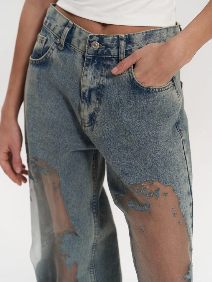 Woman modeling high waist wide leg jeans with edgy mesh panels, perfect for a chic and trendy women's fashion statement.
