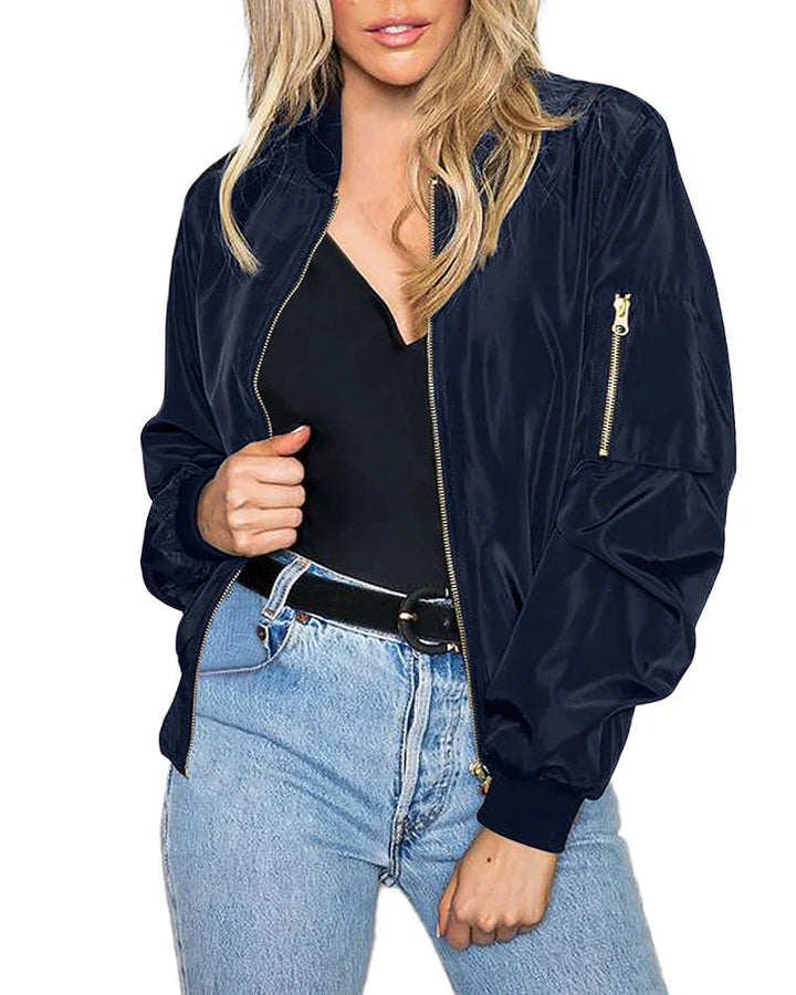 A woman wearing a stylish lightweight bomber jacket, walking outdoors with ease.