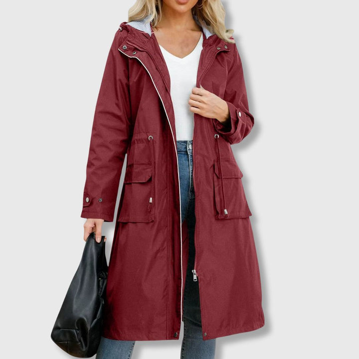 Woman in a chic long hooded rain jacket with drawstring waist, ideal for stylish spring or fall outdoor wear.