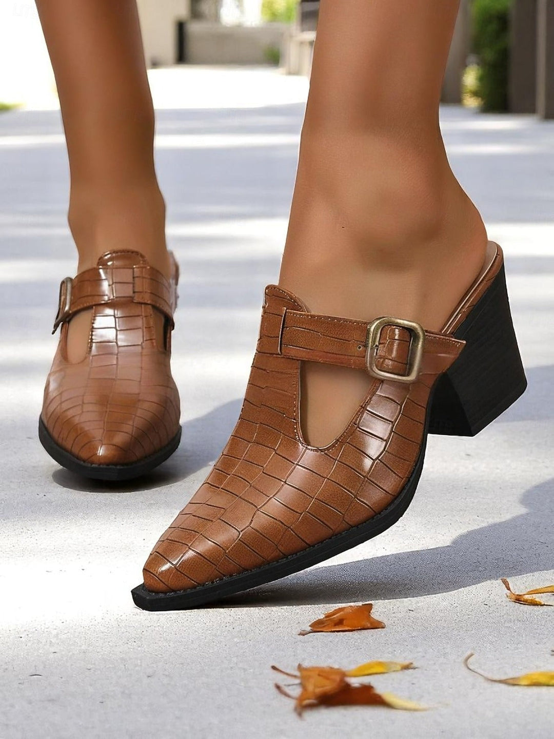 Chic women's slip-on mules featuring a sturdy block heel and modern buckle cut-out. Versatile casual footwear.