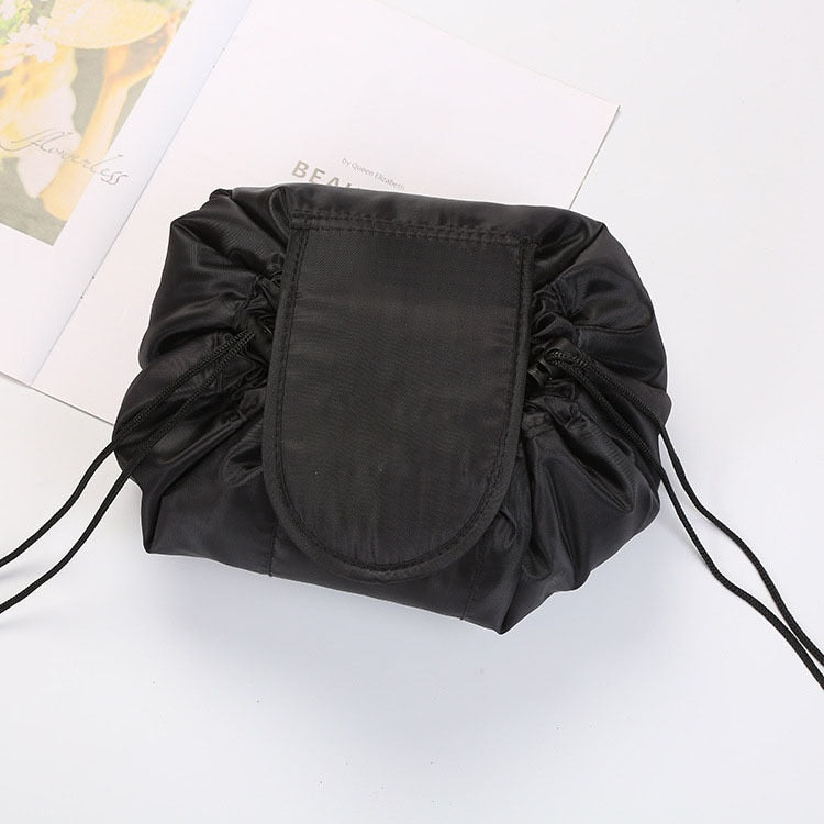 Open drawstring toiletry bag displaying women's organized makeup, brushes & travel accessories.