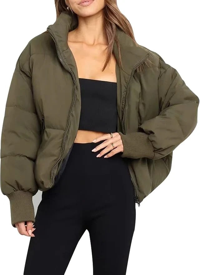 Detail of women's quilted puffer jacket, cropped, showing zip-up front & stand collar, winter fashion.