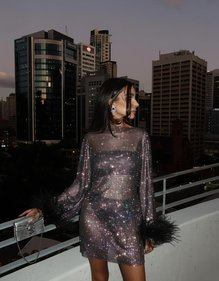 Close-up of a women's silver metallic cocktail dress with shimmering fabric, ideal for evening wear.