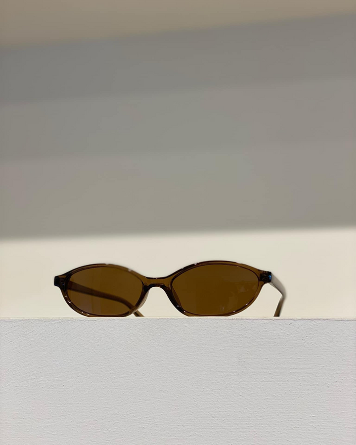 Fashionable women's sleek oval sunglasses, a must-have accessory for a retro minimalist style.