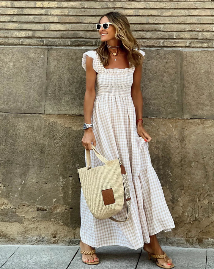 Women's smocked gingham maxi dress with delicate ruffle sleeves, perfect for elegant summer style.