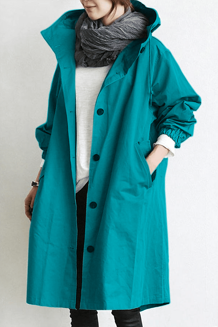Woman wearing a stylish hooded waterproof rain trench coat, walking confidently in wet weather.