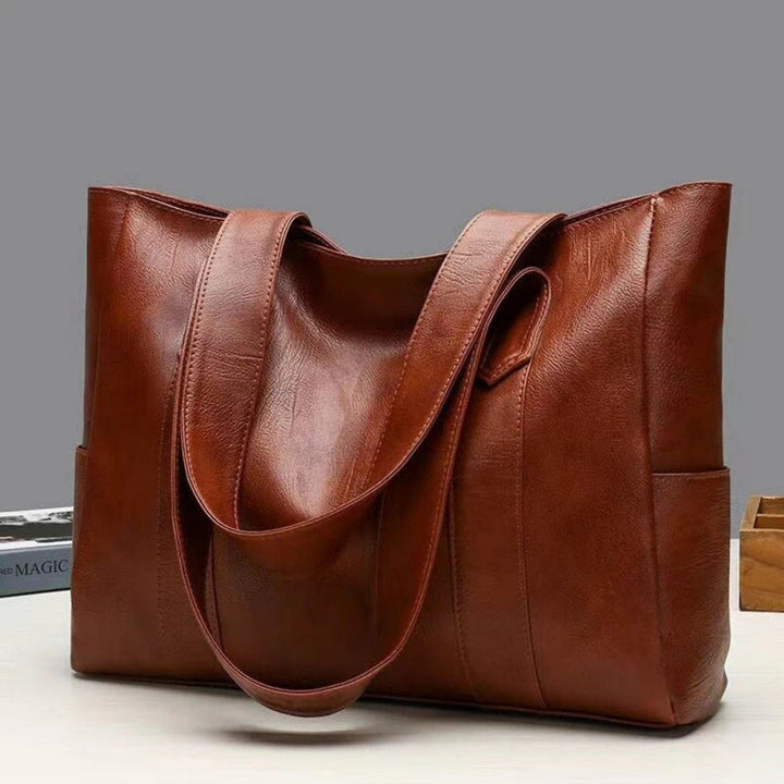 Women's leather tote bag with spacious side pockets, durable leather craftsmanship, elegant design for work or travel.