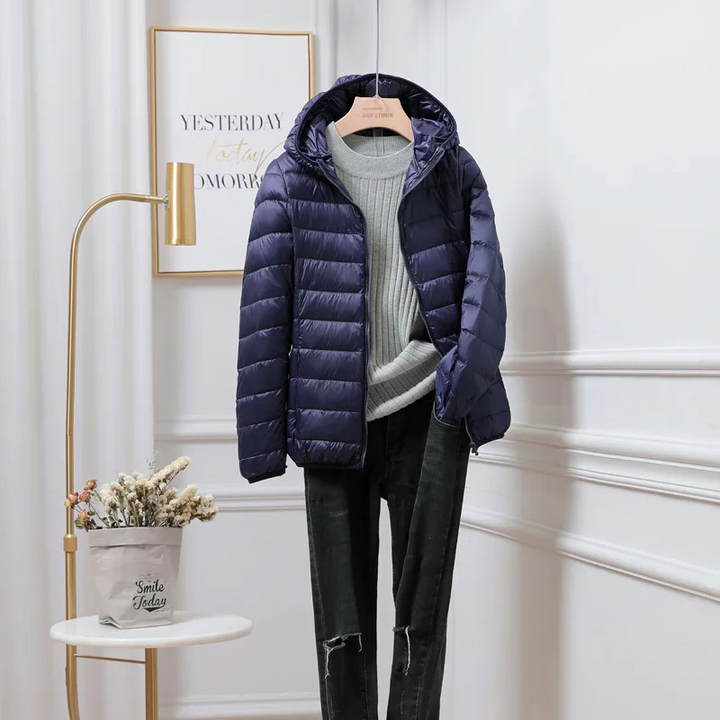 "Women's ultralight foldable puffer jacket with hood, chic design, lightweight, perfect for travel and cold weather."