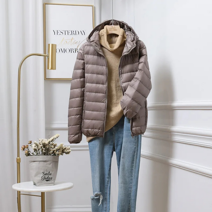 "Women's ultralight foldable puffer jacket with hood, chic design, lightweight, perfect for travel and cold weather."
