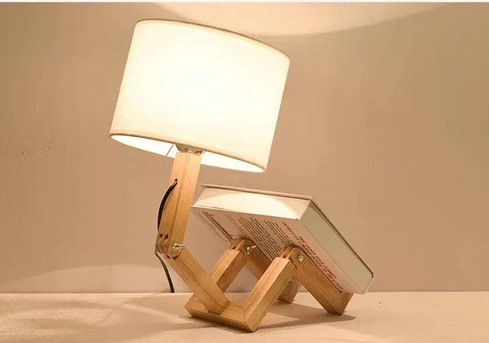 Wooden robot table lamp with integrated book holder for modern desk decor and reading.